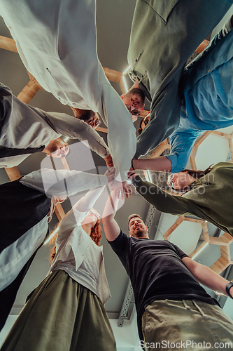 Image of A group of young businessmen offer their hands together, symbolizing togetherness in the business world