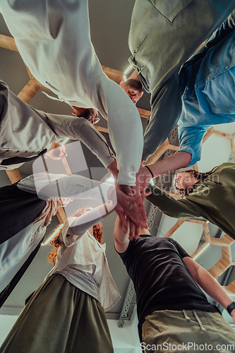 Image of A group of young businessmen offer their hands together, symbolizing togetherness in the business world