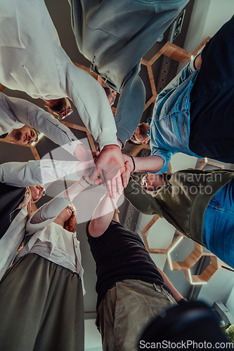 Image of A group of young businessmen offer their hands together, symbolizing togetherness in the business world