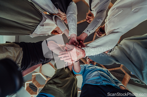 Image of A group of young businessmen offer their hands together, symbolizing togetherness in the business world