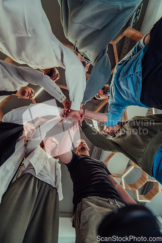 Image of A group of young businessmen offer their hands together, symbolizing togetherness in the business world