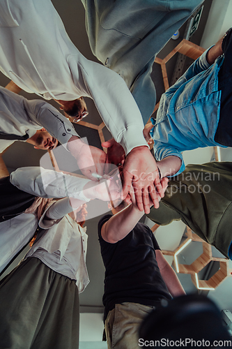 Image of A group of young businessmen offer their hands together, symbolizing togetherness in the business world