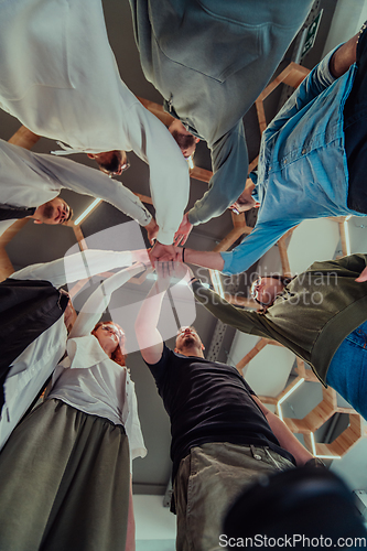 Image of A group of young businessmen offer their hands together, symbolizing togetherness in the business world