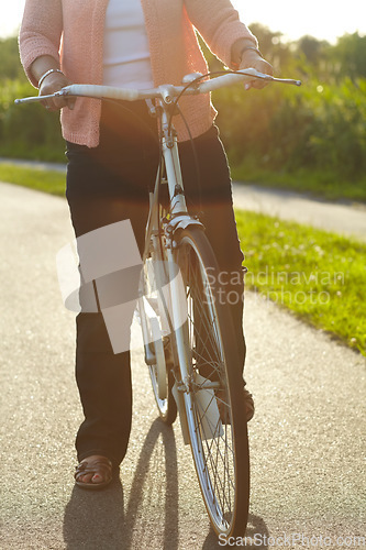 Image of Nature, fitness and woman on a bicycle for exercise, workout and training on a street in park. Sports, health and closeup of female person cycling on a bike for an outdoor adventure in a garden.