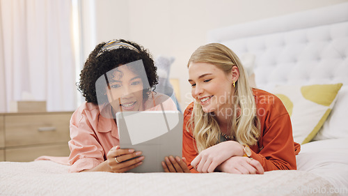 Image of Couple of friends, tablet and bedroom for social media, movie streaming service and film choice. Young women relax on bed and scroll on digital technology for video, internet and website at home