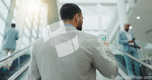 Image of Businessman, phone and travel on escalator at airport for online booking, flight time or boarding. Rear view of man checking plane schedule on mobile smartphone for business trip on moving staircase