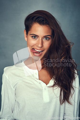 Image of Funny face, tongue and portrait of woman, silly and confident by backdrop, hair and casual fashion. Happy female person, beauty and cosmetics or goofy, care and joke or posing, comedy and crazy