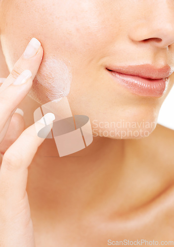 Image of Woman, face and hand with cream in skincare, beauty or cosmetics against a studio background. Closeup of female person or model smile in satisfaction for lotion, creme or facial product and treatment