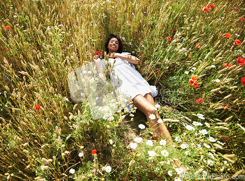 Image of Woman, flowers and laying in field, portrait and smile in spring, vacation and sunshine in nature. Girl, happy and relax with plants, floral land and outdoor in countryside with top view in summer