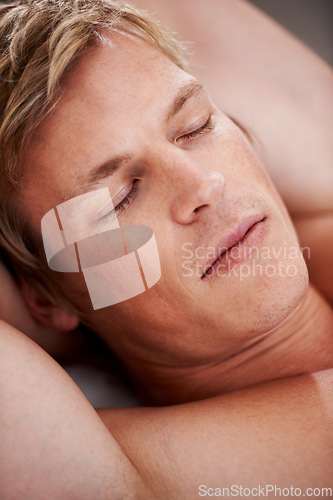 Image of Face, relax and a man sleeping in the bedroom of his home closeup in the morning for peace, rest or a nap. Wellness, dreaming and eyes closed with a young person asleep in an apartment alone