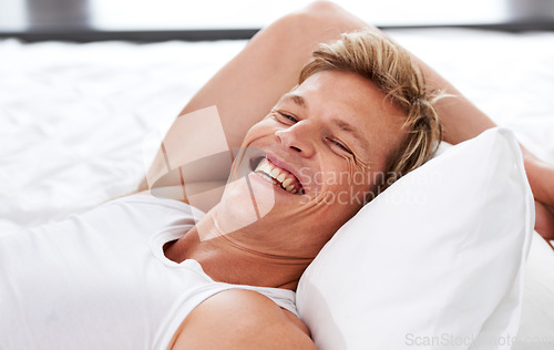 Image of Man, smile and relax in bed for confidence or casual wellness, summer break or happy. Male person, laugh and rest for weekend or vacation chill for morning zen or holiday nap, stress free in home