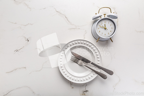 Image of Concept of intermittent fasting, empty plate with clock