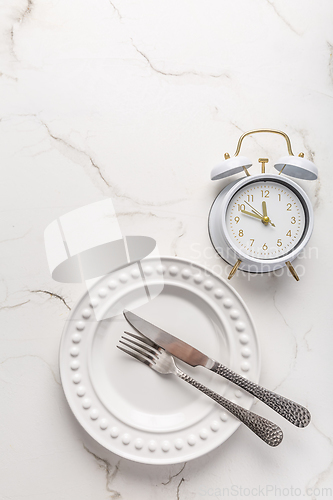 Image of Concept of intermittent fasting, empty plate with clock