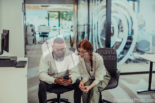 Image of In a modern office African American young businessman and his businesswoman colleague, with her striking orange hair, engage in collaborative problem-solving sessions