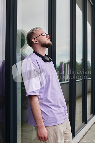 Image of In front of a modern glass building, a young, blond influencer strikes a confident pose, epitomizing urban glamour and style in the heart of the city