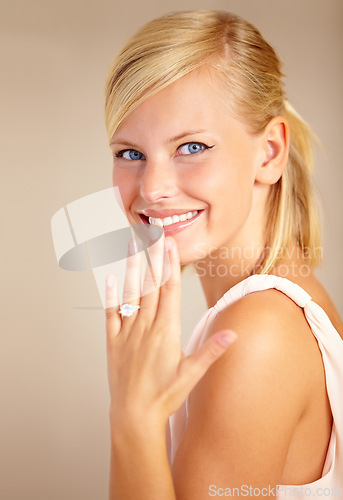 Image of Woman, happy and wedding ring in studio portrait with smile for proposal, engagement or commitment by background. Girl, model and jewelry for marriage, diamond and metal for celebration at ceremony