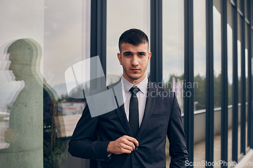 Image of A CEO dressed in a sleek black suit stands confidently at the entrance of a modern corporate building, awaiting the start of the workday in the bustling urban environment.