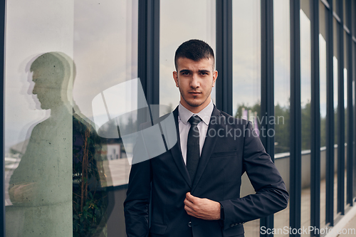 Image of A CEO dressed in a sleek black suit stands confidently at the entrance of a modern corporate building, awaiting the start of the workday in the bustling urban environment.