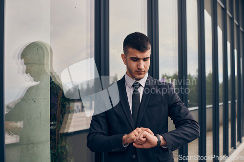 Image of A CEO dressed in a sleek black suit stands confidently at the entrance of a modern corporate building, awaiting the start of the workday in the bustling urban environment.