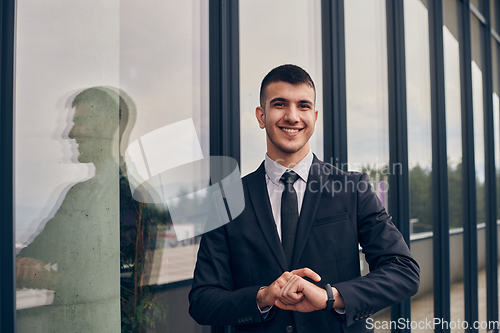 Image of A CEO dressed in a sleek black suit stands confidently at the entrance of a modern corporate building, awaiting the start of the workday in the bustling urban environment.