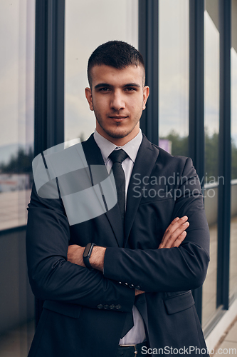 Image of A CEO dressed in a sleek black suit stands confidently at the entrance of a modern corporate building, awaiting the start of the workday in the bustling urban environment.