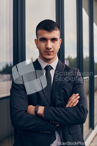 Image of A CEO dressed in a sleek black suit stands confidently at the entrance of a modern corporate building, awaiting the start of the workday in the bustling urban environment.