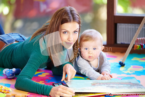 Image of Portrait, woman and baby with book in home for learning, development or cognitive growth for education. Mother, son or family with reading, bond and lying on floor in living room with toys for future