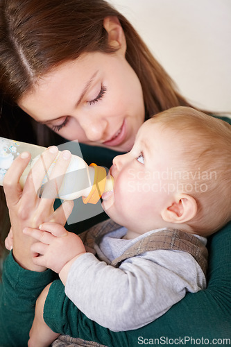 Image of Woman, holding and baby with bottle for feeding in home for growth, child development or hunger. Mother, son and bond by looking at boy for formula, food or milestone in nutrition, health or diet