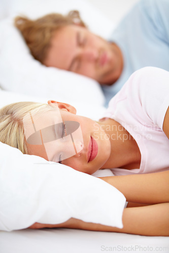 Image of Love, sleep and a couple in a bedroom in the morning to relax in their home together for holiday or vacation. Face, dreaming or eyes closed with a young woman and man in bed in their apartment