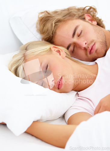 Image of Love, relax and a couple sleeping in bed in the morning in their home together for holiday or vacation. Face, dream or eyes closed to rest with a young woman and man in the bedroom of their apartment