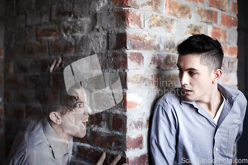 Image of Man, fear and hide by brick wall with schizophrenia, mental health and panic for ghost or haunted soul. Person, scared or anxiety for character, illusion or paranoid expression and psychological risk