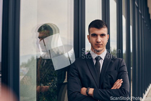 Image of A CEO dressed in a sleek black suit stands confidently at the entrance of a modern corporate building, awaiting the start of the workday in the bustling urban environment.