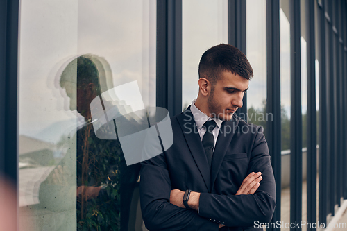 Image of A CEO dressed in a sleek black suit stands confidently at the entrance of a modern corporate building, awaiting the start of the workday in the bustling urban environment.