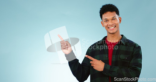 Image of Portrait, smile and man with hand pointing to studio for mockup, space or news on blue background. Presentation, smile and face of model show information, announcement or menu, guide or how to steps