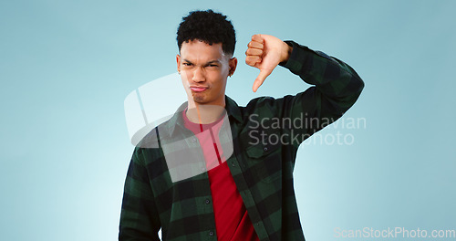 Image of Thumbs down, frown and portrait of man with hand, vote or bad review on blue background. Unhappy, face or model face with finger emoji for fail, feedback or disappointed by poor, results or rejection