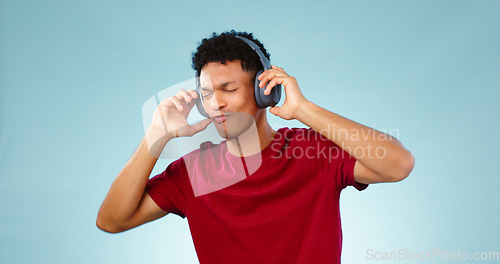Image of Man, headphones and dancing with music in studio for mock up of streaming service on blue background. Cape Town, male model and eyes closed for listening to song, podcast or radio in space with promo