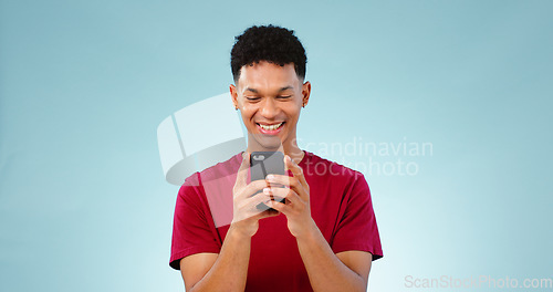 Image of Man, smile and texting on phone in studio for communication mock up on blue background. Young, person, model and Cape Town with mobile app, message or social media by internet, connection or cellular