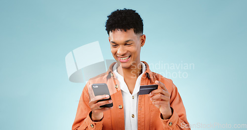 Image of Man, phone and credit card for online shopping, e commerce and digital money on a blue background. Happy student or young person with mobile app, internet banking or e learning registration in studio