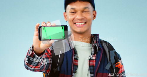 Image of Hiking, green screen and man with a cellphone, smile and happiness on a blue studio background. Person, hiker and model with adventure, mockup space or smartphone with tracking markers or digital app