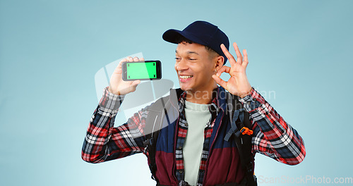 Image of Hiking, green screen and man with a smartphone, ok sign and happiness on a blue studio background. Person, hiker and model with perfect symbol, agreement and cellphone with tracking markers and smile