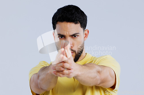 Image of Finger gun, pointing and portrait of man in studio with aim for target, shooting and spy on blue background. Secret agent, mockup space and face of person with hand gesture for pistol or weapon