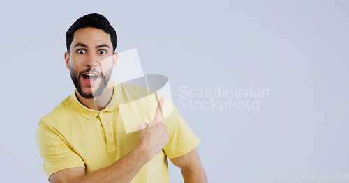Image of Man, portrait and pointing up in surprise on mockup for deal, advertising or marketing against a gray studio background. Shocked or surprised male person or model showing notification, alert or sale