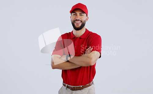 Image of Happy man, portrait and professional delivery guy with arms crossed in confidence against a gray studio background. Male person, model or courier worker smile with red hat for service on mockup space