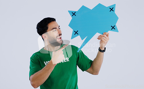 Image of Man, speech bubble and volunteering in studio with paper, point or smile for opinion by background. Person, sign or poster with mockup space, tracking markers or feedback for promotion, quote or idea