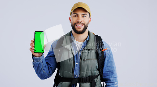 Image of Happy man, backpack and phone green screen on mockup or hiking app against a studio background. Portrait of male person or hiker smile with bag and showing mobile smartphone display or travel tips