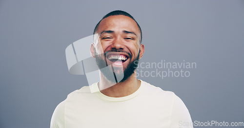 Image of Face, happy or man laughing at a funny joke or crazy humor in studio isolated on gray background. Freedom, excited model or silly male person with a goofy smile, joy or positive energy to relax alone