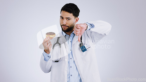 Image of Man, doctor and thumbs down for donut choice in studio and unhealthy snack in mockup. Mexican person, nutritionist and portrait or no, advice and opinion on diet, fail and food by gray background