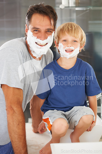 Image of Two of a kind. A young boy and his father both with shaving cream on their faces.