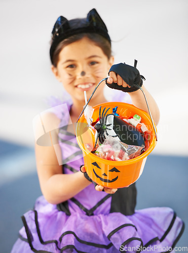 Image of Want some Halloween candy. Little girl dressed in a Halloween costume holding a candy bucket.