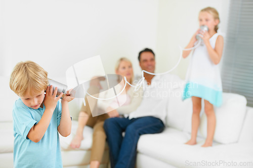 Image of This really works. A little boy shouting loudly into a tin can connected to another that his sister is holding.